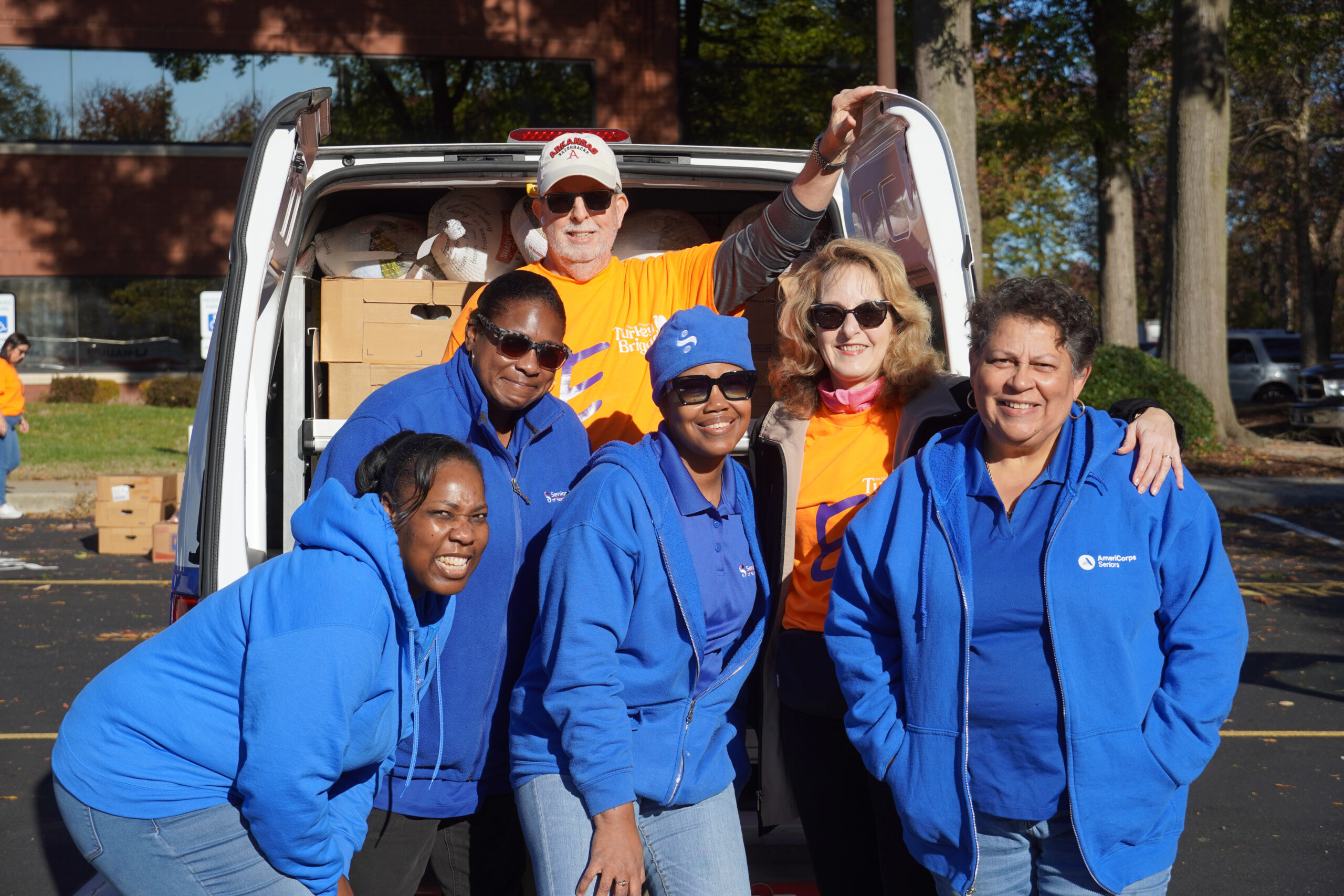 group posing in front of truck filled with thanksgiving supplies