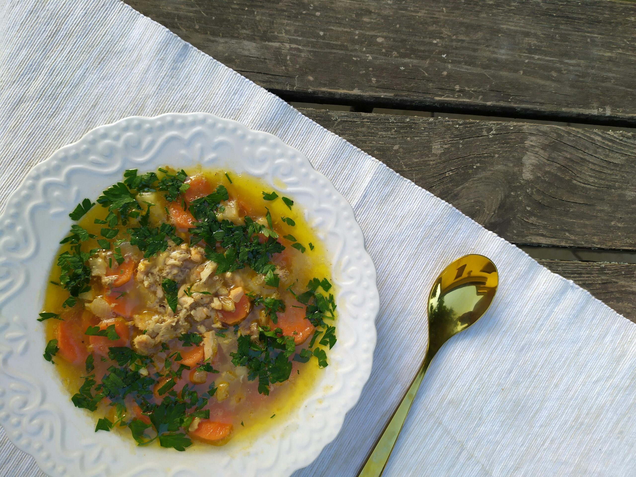 chicken soup in a white bowl on a white napkin with a spoon