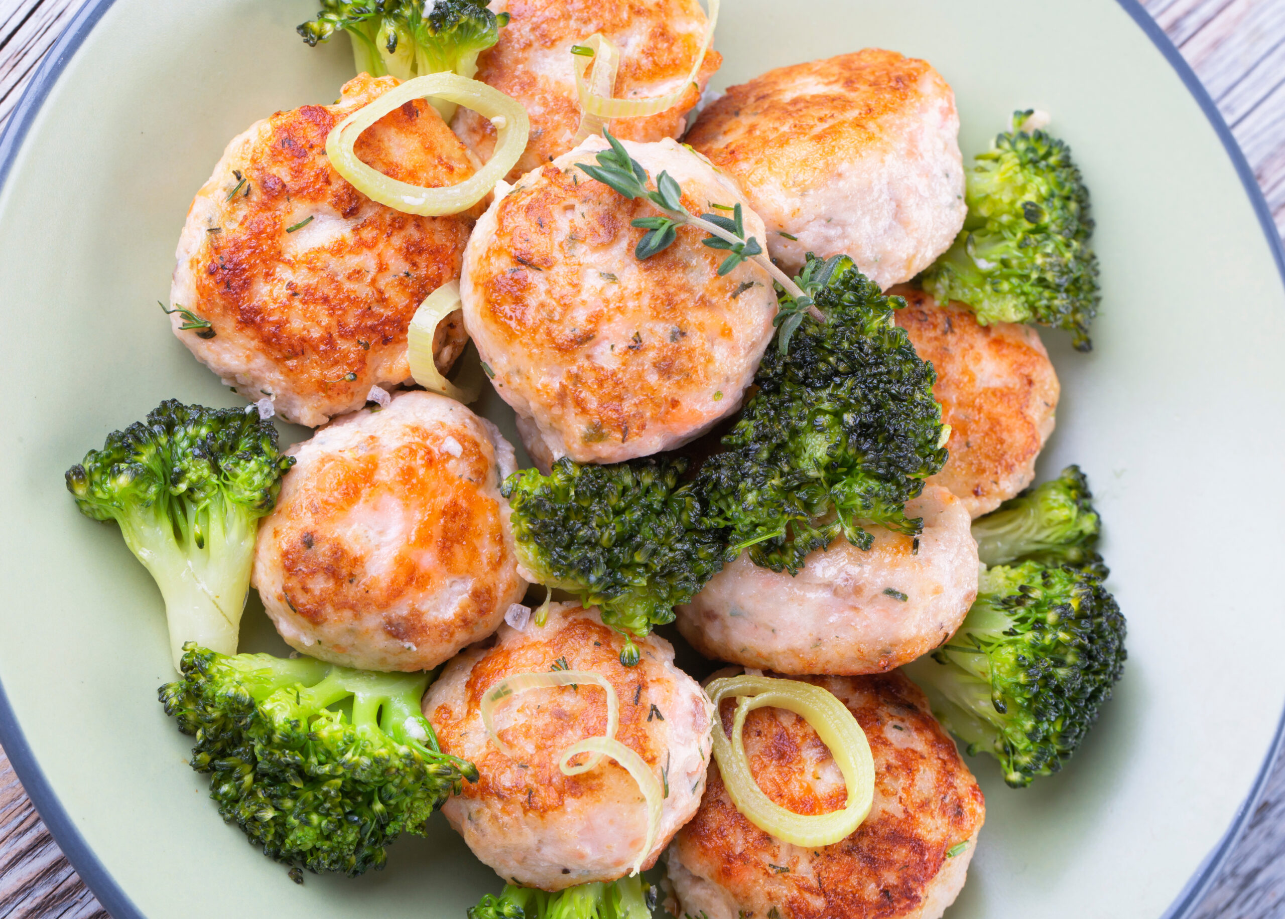 Plate of salmon meatballs with vegetables on a wooden table